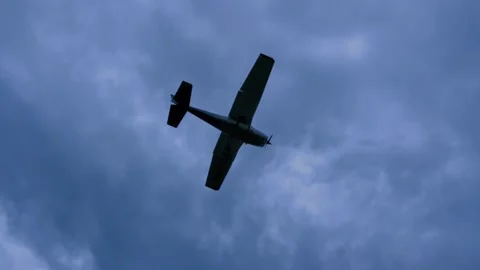 Small Aircraft Flying Across Cloudy Blue Sky Stockbeeldmateriaal 343246425