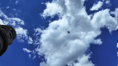 Small Airplane Flying in Blue Sky with Clouds and Building Below 스톡 동영상 307556898