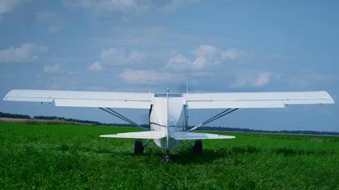 Small airplane starting engine standing on countryside green field sunny day Foto stock