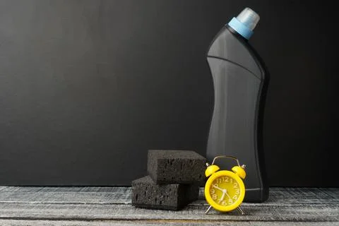 Small alarm clock, a stack of dishwashing sponges and a plastic bottle on a b Stock Photos