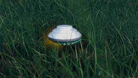 Small Alien flying object landing on a grass field. Stock Footage 245541416