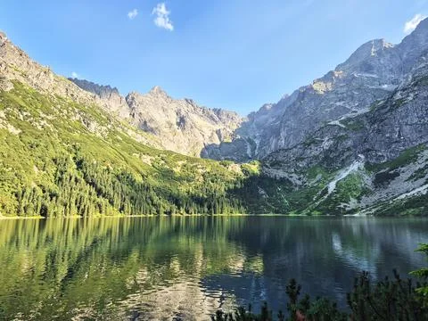 Small alpine lake surrounded by evergreen-covered slopes and dramatic rocky.. Stock-Fotos