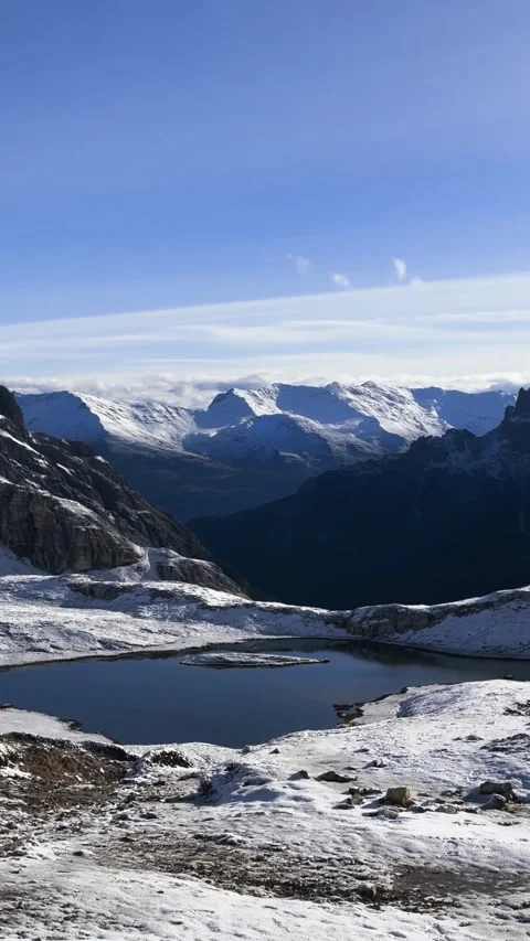 Small alpine lake surrounded by snowy mountains in Dolomites near Tre Cime. Video stock 330437426