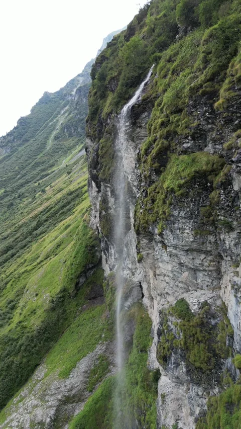 Small Alpine Waterfall Flowing Over Rocky Ledge – 4K Vertical Drone View Stock Footage 328706421