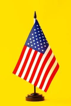 Small American flag on a black base against a bright yellow background Stockfoto's