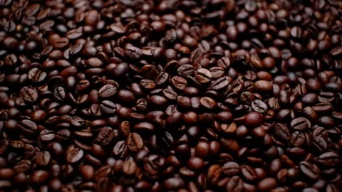 A small amount of coffee beans falling into a pile of coffee beans. Close-up. Stock Footage 156210002