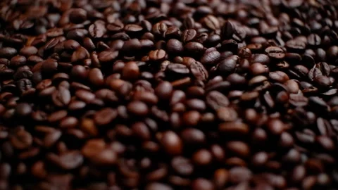 A small amount of coffee beans falling into a pile of coffee beans. Close-up. Stock Footage 156225545