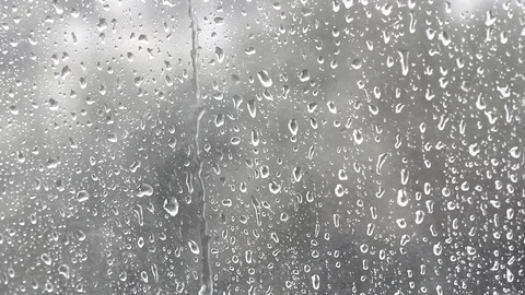 Small and large drops of rain or water flow down a light transparent window Stock Footage 119447172