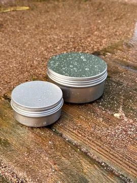 Small and large silver cans on wooden stand, around water, spray Stock Photos