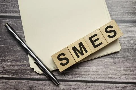 Small and medium-sized enterprises Word Written In Wooden Cubes on notebook.. Stock Photos