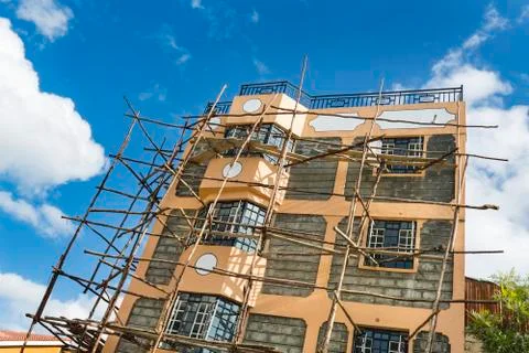 A small appartment building under construction with typical local scaffolding Stock Photos