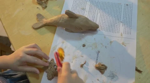 Small Apprentice Girl is Using Some Thin Stick to Shape a Piece of Clay to Make Video stock 59123796