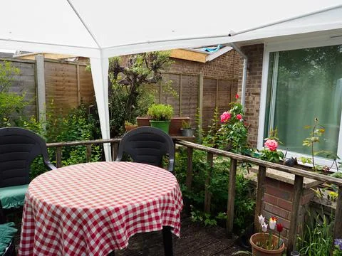 A small area of decking in a back garden covered with a white gazebo and showing Stock Photos