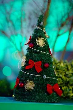 A small artificial Christmas tree decorated with red bows, balls and golden.. Stock Photos