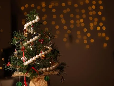 Small artificial Christmas tree decorated with ornaments and lights placed .. Stock Photos