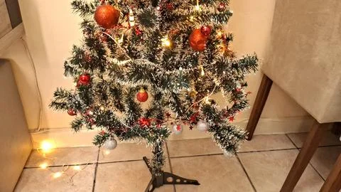 Small artificial christmas tree decorated with red and silver ornaments Stock Photos