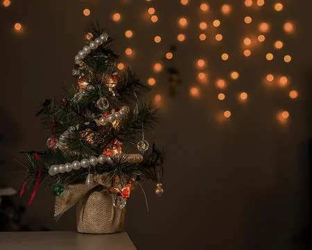 Small artificial Christmas tree with decorations and lights set up on a tab.. Fotos Stock