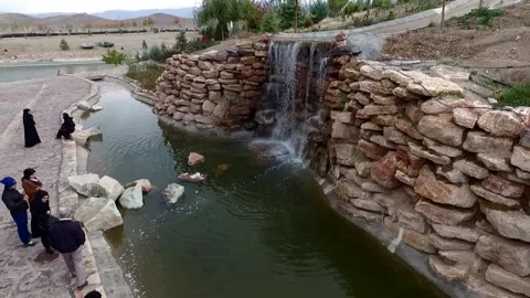Small artificial waterfall in beautiful lake and modern island. boating people. Stock Footage 287712409