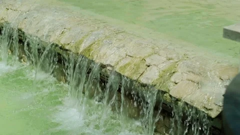 Small artificial waterfall with clear blue water flowing over steps, a beautiful Stock Footage 279163998