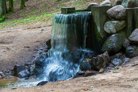 Small artificial waterfall in the park. Stock Photos