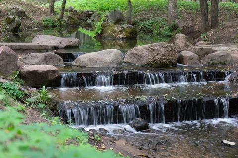 Small artificial waterfall in the park. Stock Photos