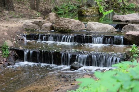Small artificial waterfall in the park. Stock Photos