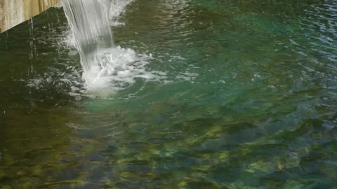 Small artificial waterfall. Transparent water surface in the city fountain. Video stock 142216946