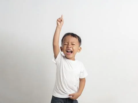 Small asian boy points his finger upward while shouting loudly with a wide .. Stock Photos