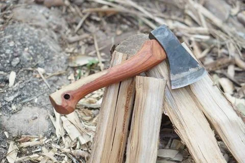 Small axe resting on split firewood in outdoor setting. Wooden handle and steel  Stock Photos
