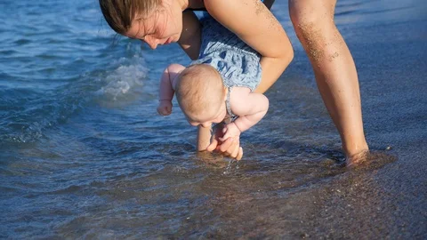 Small baby infanf first time at the sea. mother washes the hands of a child Stock Footage 99150870