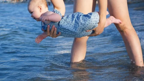 Small baby infanf first time at the sea. mother holds the baby above the water Stock Footage 99151056