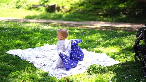 Small baby plays with a jacket, trying to put it on, crawling on a blanket on Stock Footage 256154651