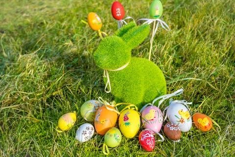 Small baby rabbit and easter eggs in the fresh, green spring landscape. Stock Photos