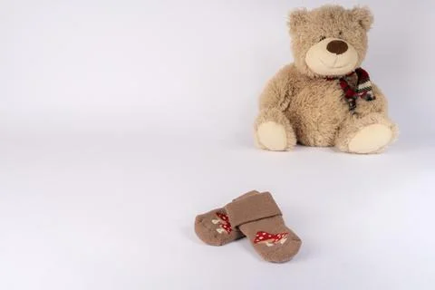 Small baby socks with mushroom patterns placed near a fluffy teddy bear sit.. 스톡 사진