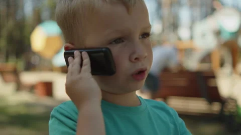Small baby using a phone in a park. Kid talking on an old telephone outside. Video stock 343208981