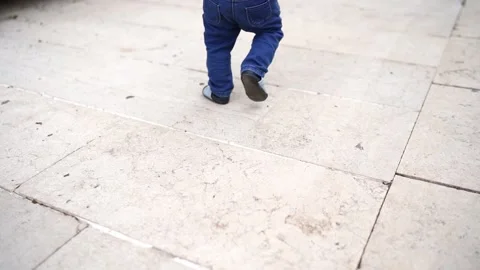 Small baby walks on tiles in tiny shoes. Back view. Cropped Stock Footage 233174437