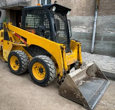 Small backhoe loader parked on a construction site.  Stock Photos
