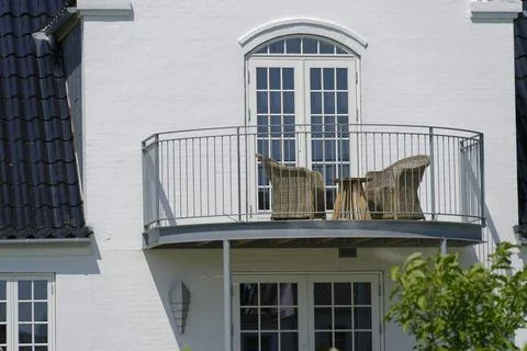 Small balcony with table and chairs on white house Stock Photos