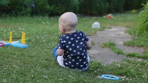 A small bald toddler quickly crawls on the grass in the summer Stock Footage 166063343