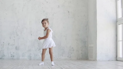 A small ballerina in a white pack is danced on a light background in the studio Stock Footage 94339561