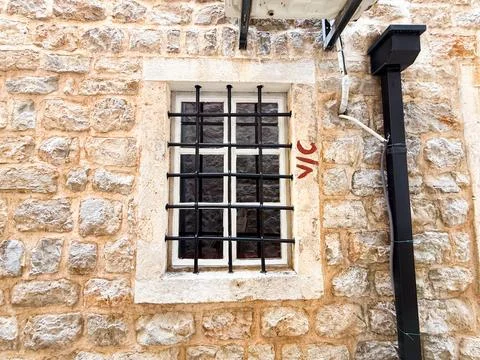Small barred window in a rustic stone facade. Architecture, security, tradi.. Stock Photos