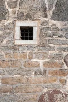 Small barred window in stone wall, historic architecture detail Stock Photos
