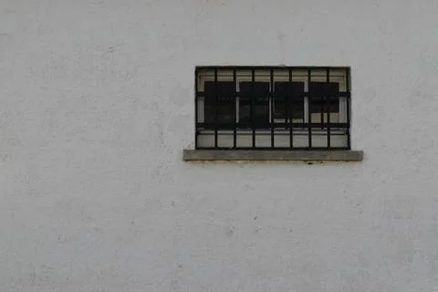 Small barred window on white wall Stock Photos