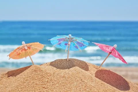 Small beach umbrellas on a beach on a background of the sea. Stock Photos