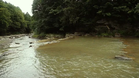Small beautiful river flows between rocks and trees. A perfect spot for fishing Stock Footage 65745997