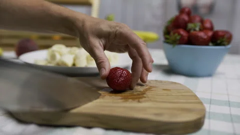 Small, beautiful strawberry being sliced on cutting board with knife - closeup, Stock Footage 341257911