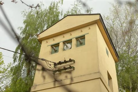Small beige utility building with transformers and insulators among trees Stock Photos