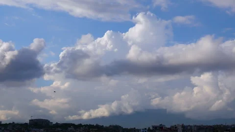 A small bird flying through, huge white clouds in the background Stock Footage 258536373