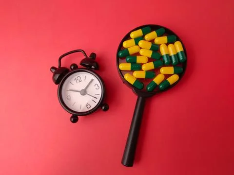 A small black alarm clock sits to the left of a magnifying glass framing me.. 库存照片