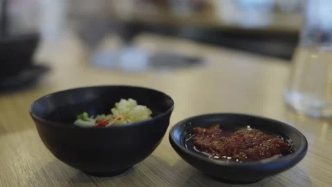 Small black ceramic bowls containing minced garlic and spicy red chili past.. Stock Footage 335939736